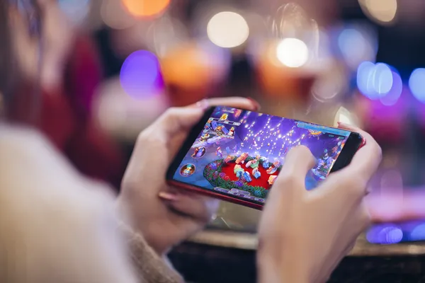 A young woman relaxing with her phone while dynamic casino elements float around her, illustrating the smooth mobile experience offered by the 520JL app.