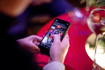 A cheerful woman in traditional clothing using her smartphone during a festive moment, showing how easily the 520JL app fits into everyday life.