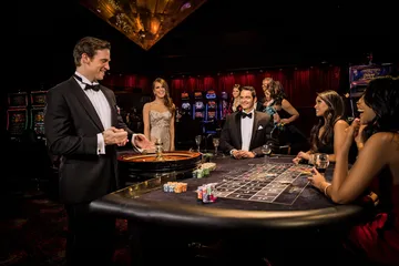 A professional dealer in a tuxedo greeting players at the roulette table, symbolizing the authentic live casino feel at 520JL.